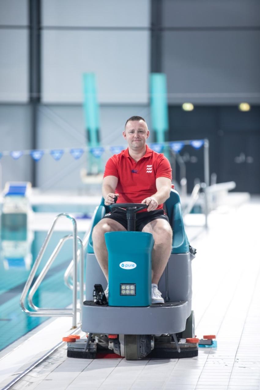 Man op schoonmaakmachine in het zwembad