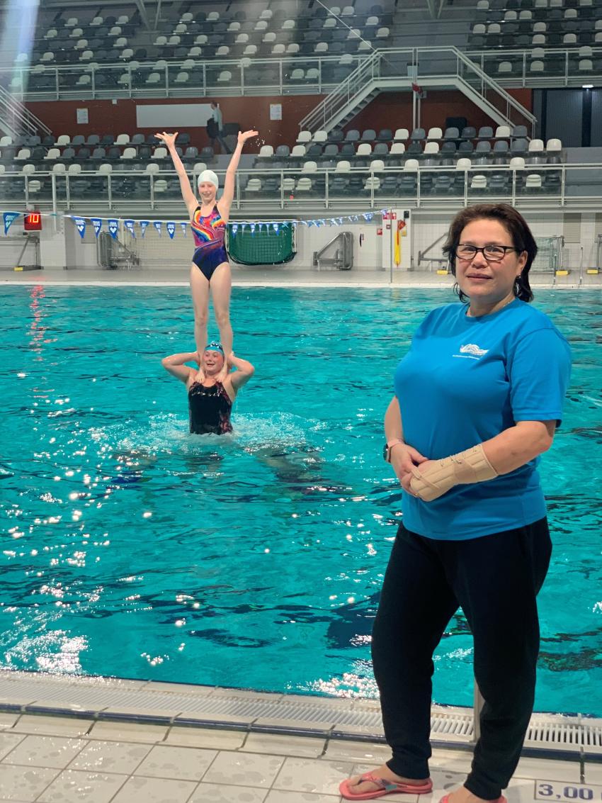 Trainster Ingrid van Vuuren met twee synchroonzwemsters op achtergrond