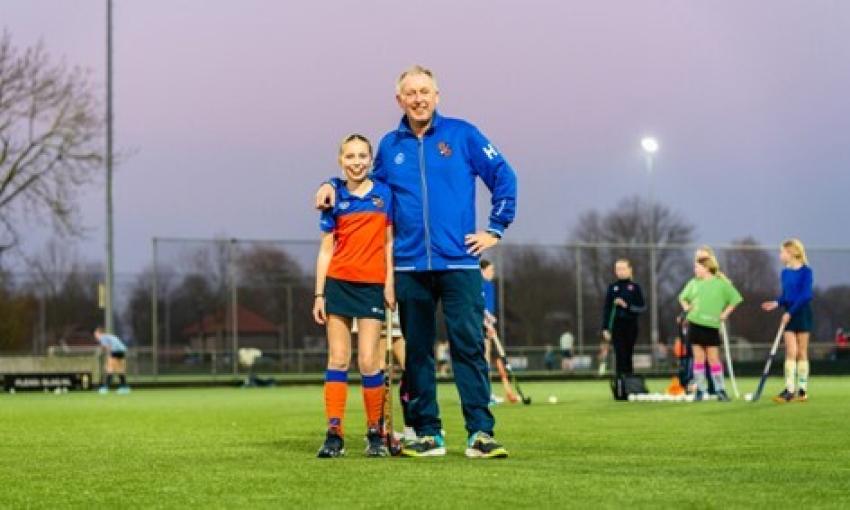 Man en meisje op een hockeyveld