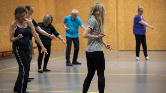 Mensen in kring die een oefening doen, klik voor een vergroting