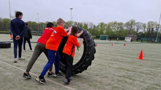 Kinderen duwen een zware band vooruit tijdens Koningsspelen 2025, klik voor een vergroting