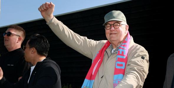 Man met heldensjaal die zijn arm omhoog steekt