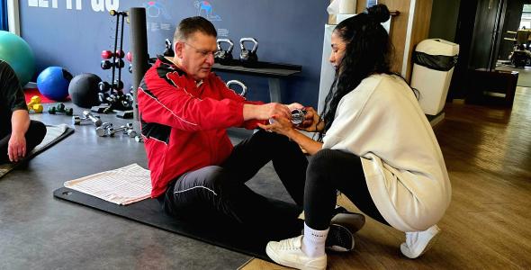 Man in beweging onder begeleider van trainer