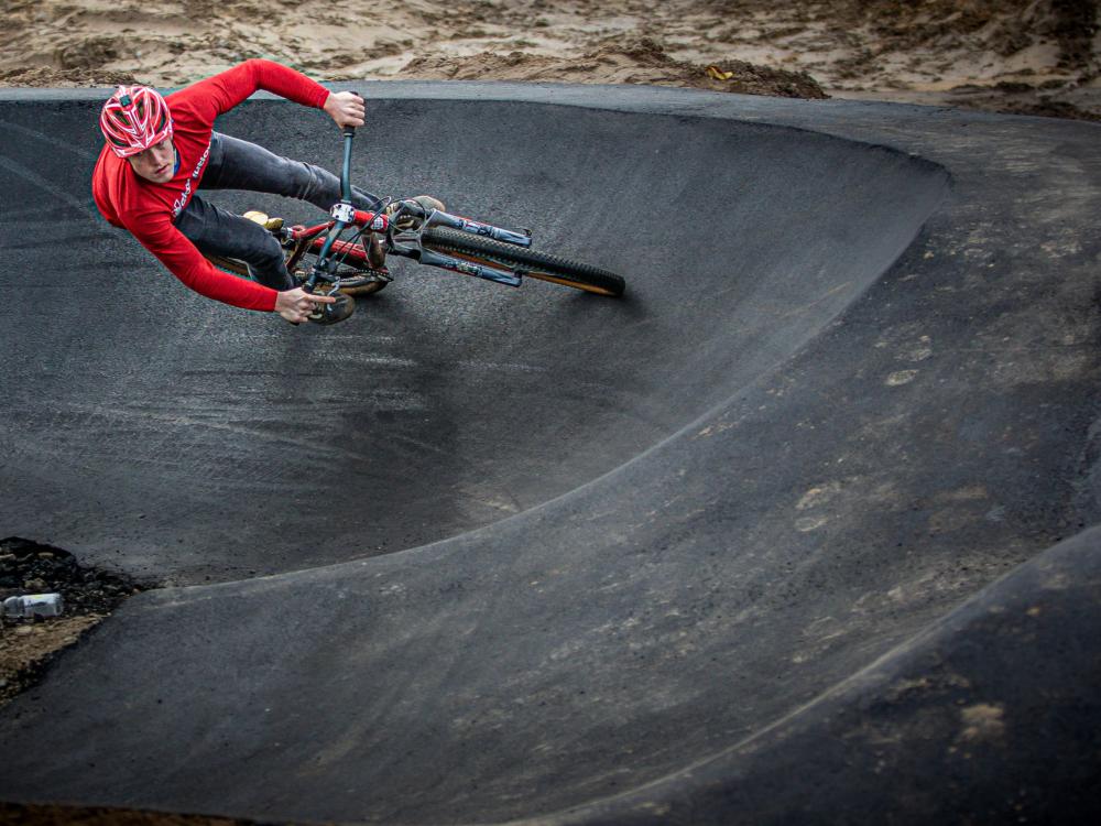 Man op BMX fietst in pumptrackbaan in het Urban Sportpark