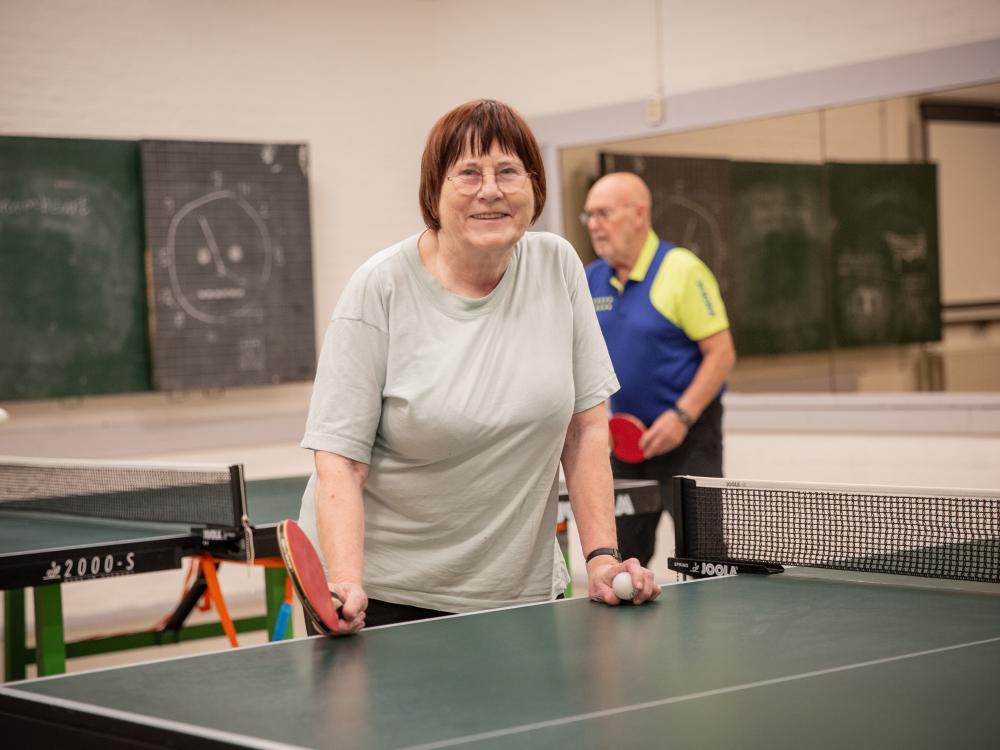 Tafeltennisster Josée aan een tafeltennistafel met op de achtergrond man die ook aan het spelen is